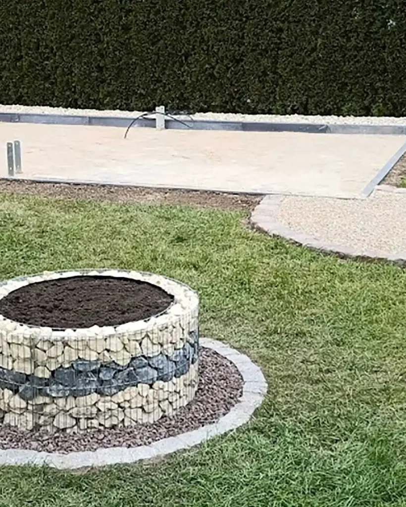 Garten- & Landschaftsbau Abitzsch in Merseburg - Leistungen - Umgestaltung Gartenbereich mit einem runden Gabionenhochbeet und einem vorbereiteten Fundamentbereich.